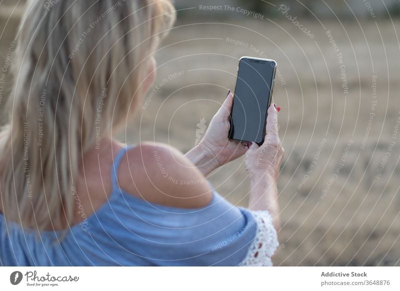 Zufriedene Frau bei Sonnenuntergang auf dem Land Feld Selfie Landschaft Smartphone benutzend malerisch ländlich Foto getrocknet Gerät Apparatur Natur Wiese