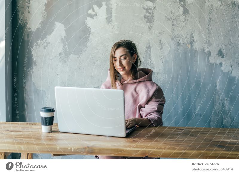 Weibliche Freiberuflerin tippt auf Laptop in der Nähe einer schäbigen Betonwand Netzwerk Tippen Surfen Internet Wand Kaffee benutzend Apparatur Gerät zuschauend