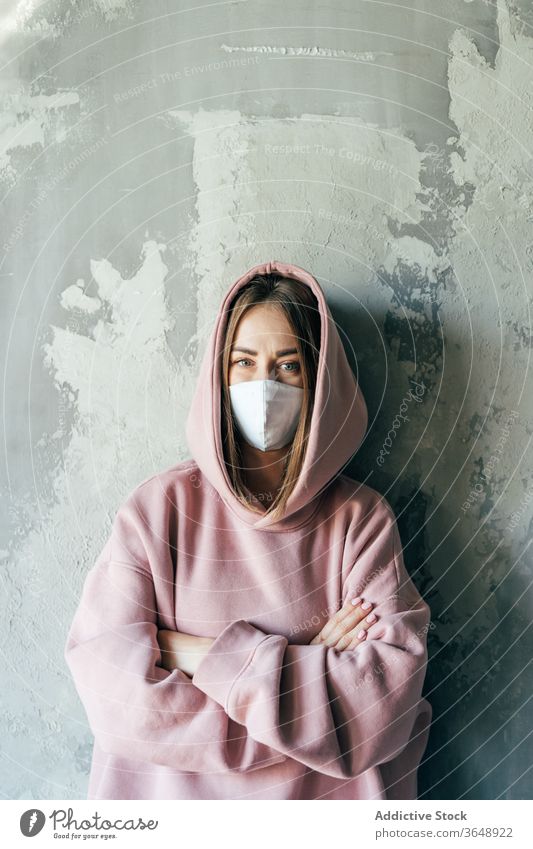Frau mit steriler Maske steht während der Quarantänezeit in Wandnähe Mundschutz Selbstisolierung Unzufriedenheit Coronavirus zu Hause Beton heimisch