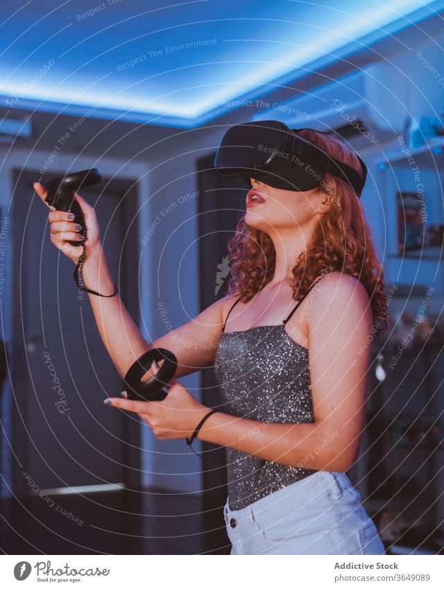 Anonyme Frau spielt zu Hause ein Spiel mit VR-Brille Headset Erfahrung unterhalten Regler Videospiel eintauchen Mund geöffnet neonfarbig benutzend Schutzbrille
