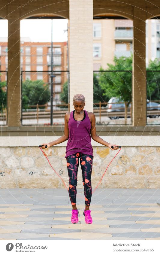 Schwarze Sportlerin springt während des Trainings auf einer Böschung in der Stadt Seil Athlet springen Aufwärmen Übung Sportkleidung Großstadt üben Gesundheit