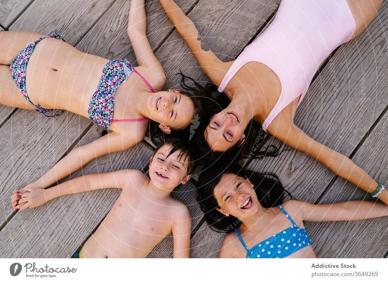 Glückliche Geschwister und Mutter am Kai liegend Kinder Urlaub Sommer Pier sich[Akk] entspannen Stern Form Lügen Badebekleidung Inhalt ruhen Händchenhalten