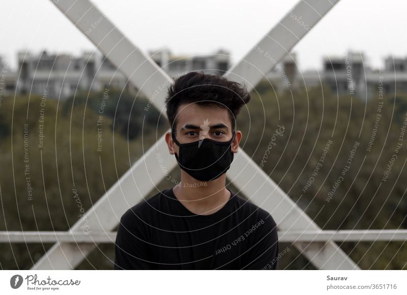 Ein junger Mann trägt eine schützende Gesichtsmaske, um eine Coronavirus-Infektion in einer Stadt zu vermeiden. Bund 19 junger Erwachsener Mundschutz Großstadt