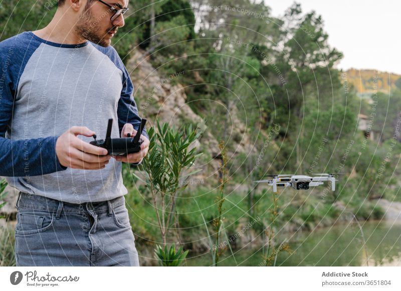 Fokussierter Mann steuert Drohne aus der Ferne Kontrolle Dröhnen Fliege abgelegen arbeiten Quadrokopter Regler Gerät unbemannt Flug männlich Landschaft