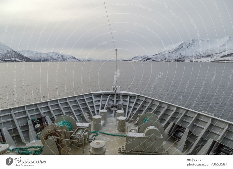 Schiffsbug mit Sicht auf die Lofoten in Norwegen Schifffahrt Meer Nordmeer Skandinavien Winter Berge Schnee Himmel Wolken Bedeckt Kalt Reise Urlaub Seil Winde