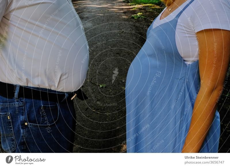Alter Mann und schwangere Frau wetteifern mit ihrem Bauchumfang Bäuche dick Schwangerschaft Wettstreit Maß nehmen Dicke Mutterschaft Erwachsene erwartend