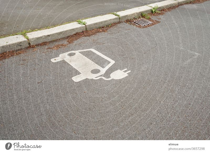 am Straßenrand befindet sich ein weißes Elektroauto - Symbol  als Hinweis für eine Ladestation Elektromobilität umweltfreundlich Autofahren Energie