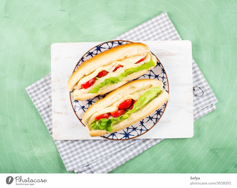 Baguette-Sandwich mit Tomaten und Käse Belegtes Brot U-Boot Mittagessen Sub hoagie flache Verlegung geschmolzen Gemüse Draufsicht Salatbeilage hölzern grün