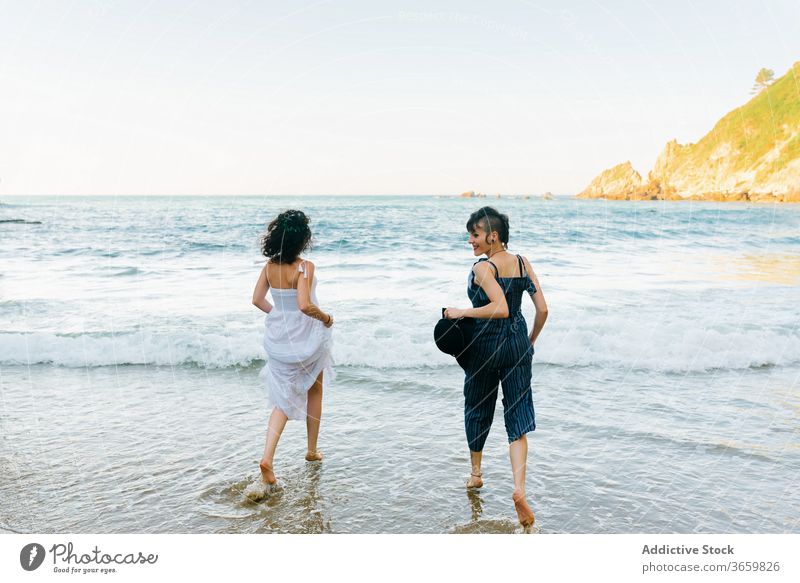 Glückliche Frauen rennen auf schäumender See in Küstennähe laufen MEER Strand Urlaub Freund Tourismus Spaß Barfuß unterhalten Freundin Harmonie Meer