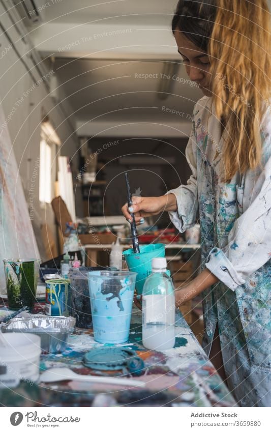 Weibliche Kunsthandwerkerin arbeitet mit Farben in der Werkstatt Künstler Frau Palette kreativ Werkzeug Talent vorbereiten Handwerk Pinselblume farbenfroh jung