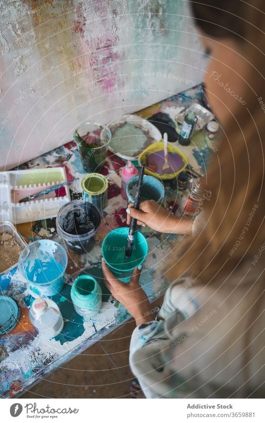 Weibliche Kunsthandwerkerin arbeitet mit Farben in der Werkstatt Künstler Frau Palette kreativ Werkzeug Talent vorbereiten Handwerk Pinselblume farbenfroh jung
