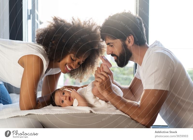 Zärtliches Streicheln eines Babys aus mehreren Rassen niedlich Familie heimwärts spielen Angebot Sofa neugeboren Zusammensein Eltern multiethnisch