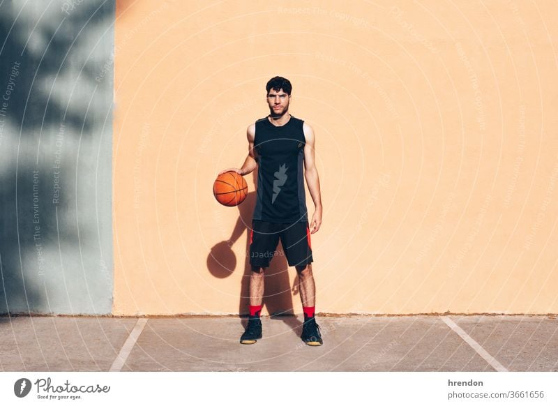 Basketballspieler mit dem Ball vor einer Wand Sport Konkurrenz Spiel sportlich wettbewerbsfähig spielen Spielen Übung männlich trainiert. anstrengen Hobby