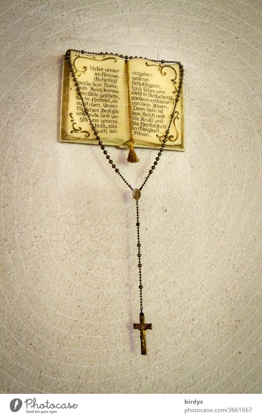 Ein Rosenkranz hängt an einem christlichen ,aufgeschlagenen Gebetsbuch mit  dem Vaterunser - Gebet - ein lizenzfreies Stock Foto von Photocase