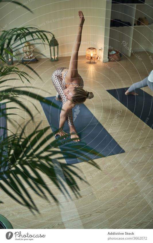 Konzentrierte Frau führt im Studio eine Yoga-Asana an der Longe mit ausgestrecktem Arm aus üben Atelier Ausfallschritt mit nach oben gestrecktem Arm beweglich