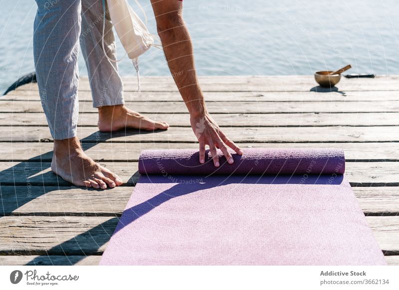 Mann mit Yogamatte auf dem Pier an einem sonnigen Tag Unterlage Klangschale meditieren hölzern Stauanlage MEER Gesundheit üben Harmonie sich[Akk] entspannen