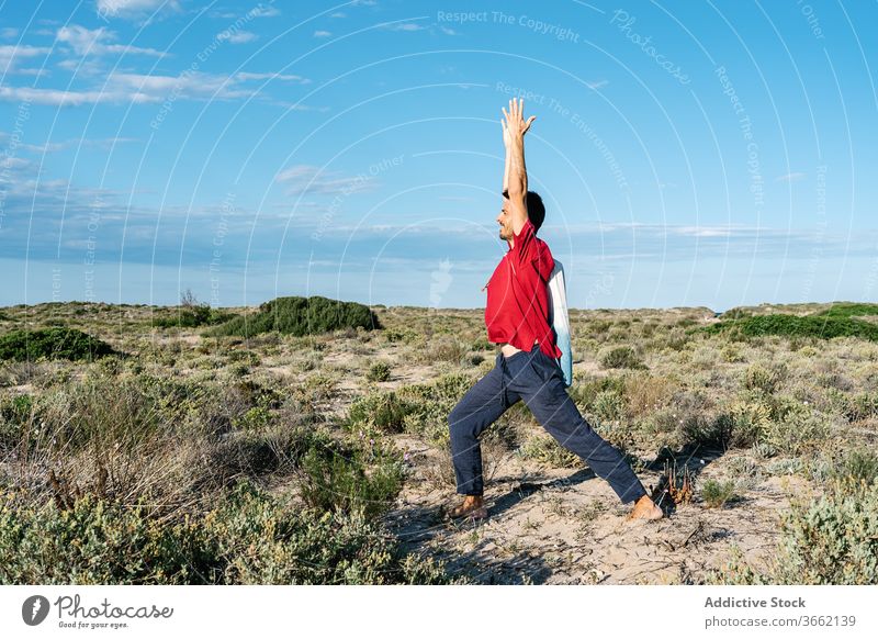 Männlicher Turner, der während des Yogatrainings in der Natur Beine und Arme streckt Mann Dehnung Asana Sand Gelände Gleichgewicht üben Übung