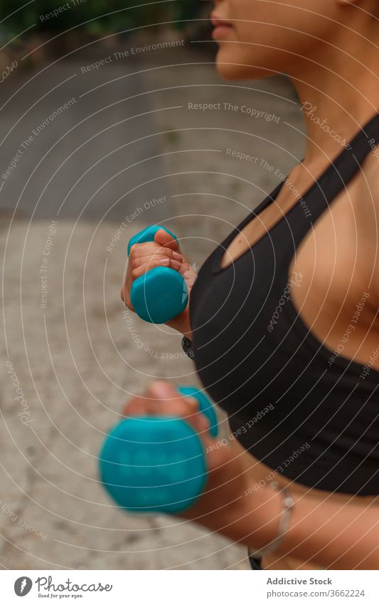 Fitnesstraining für ethnische Sportlerinnen mit Kurzhanteln auf der Böschung während des Trainings Kniebeuge Gleichgewicht erreicht Arme Straßenbelag Dehnung
