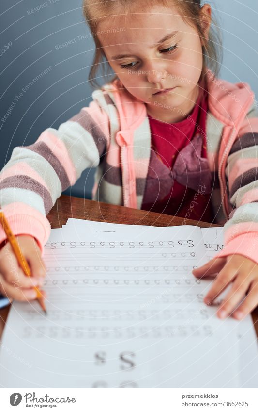 Kleines Mädchen im Vorschulalter lernt widerwillig, Briefe zu schreiben. Kind, das Briefe schreibt und widerwillig eine Schularbeit erledigt. Konzept der Früherziehung