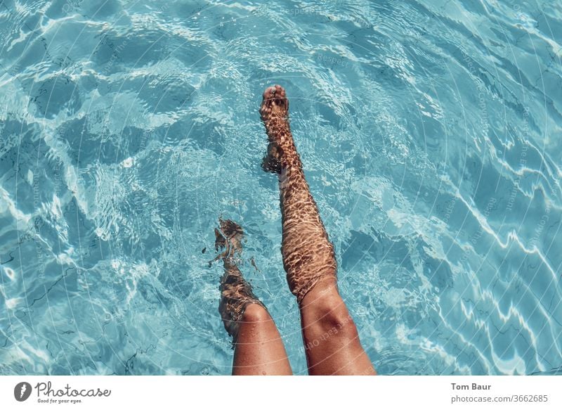 schöne braungebrannte Beine einer Frau plantschen im Pool mit leichten Wellen und schönen Spiegelungen auf den Beinen und der Wasseroberfläche frau jung pool