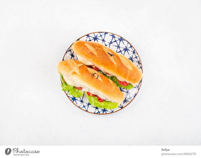 Baguette-Sandwich mit Tomaten und Käse Belegtes Brot U-Boot Mittagessen Sub hoagie flache Verlegung geschmolzen Gemüse Draufsicht Salatbeilage hölzern