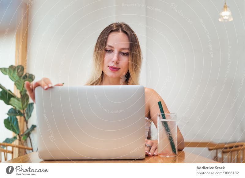 Junge Geschäftsfrau benutzt Laptop während Fernarbeit im Café Frau Arbeit freiberuflich abgelegen Tippen beschäftigt frisch Limonade Browsen Internet jung