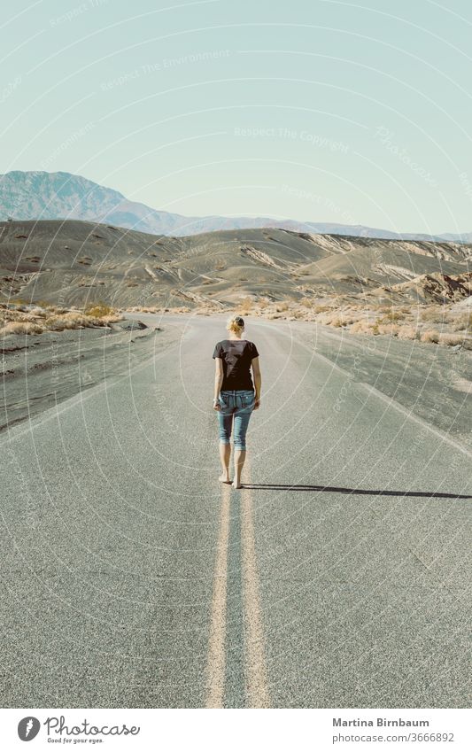 Eine Frau geht barfuss auf einer leeren Strasse im Death Valley laufen eine Person Kaukasierin Tal des Todes der Weg nach vorn Fluchtpunkt Freiheit Landschaft