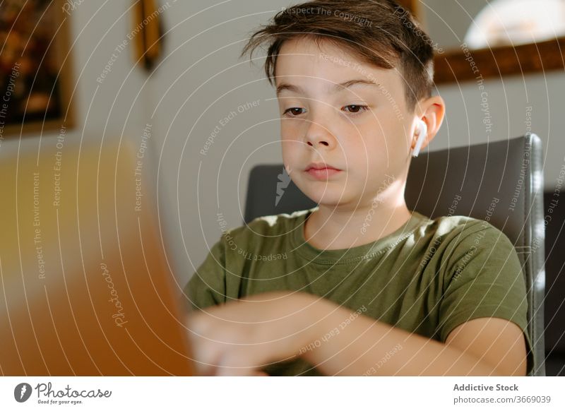 Fokussiertes Kind benutzt Laptop zu Hause Junge Tippen Tisch heimwärts benutzend Internet Gerät Apparatur Browsen online Anschluss wenig lässig Kindheit klug