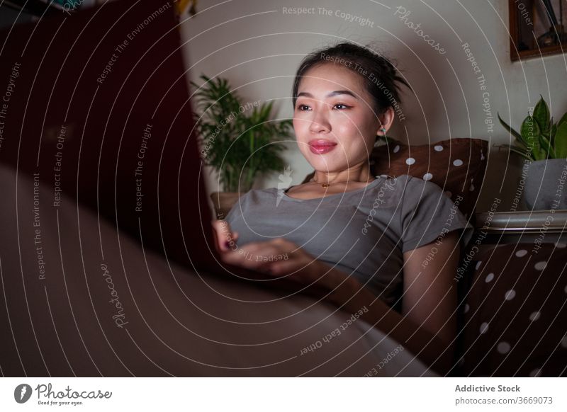 Asiatische Frau sitzt im Bett mit Laptop in der Nacht sich[Akk] entspannen Internet Komfort heimisch sitzen benutzend Gerät Apparatur Netbook genießen