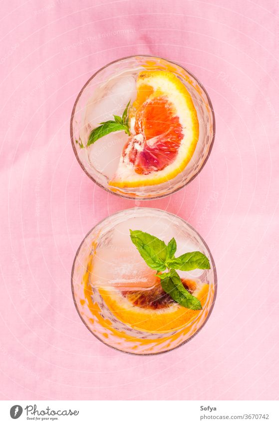 Sommerliches geeistes Zitrusgetränk mit Minze auf rosa Serviette trinken Zitrusfrüchte Wasser Cocktail Limonade aufgegossen Entzug Blutorange Kalk Frucht Saft