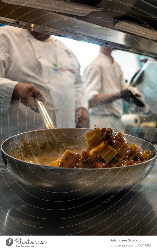 Anonymer Koch, der eine Schüssel auf einer Bratpfanne anrührt Küchenchef mischen Bestandteil Pfanne Restaurant Speise Lebensmittel kulinarisch lecker Abendessen