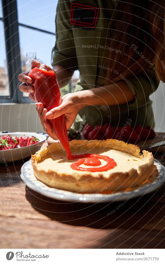 Crop Frau dekorieren Kuchen mit Sahne Spritzbeutel drücken Pasteten Koch Konditorei selbstgemacht lecker Tisch Hausfrau Lebensmittel schmackhaft heimwärts süß