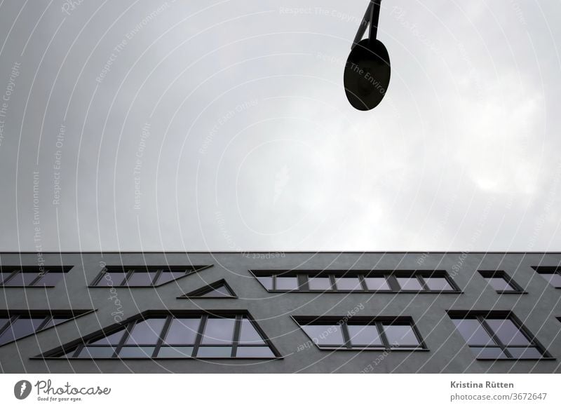 modernes gebäude und eine laterne mit grauem wolkenhimmel haus architektur fassade bürogebäude fenster stadt städtisch immobilie urban abstrakt bewölkt spitz