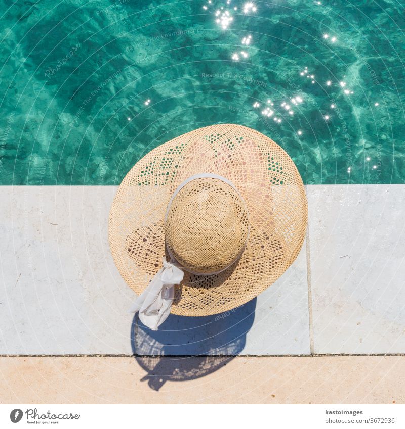 Frau mit großem Sommersonnenhut entspannt sich am Pier am klaren türkisfarbenen Meer. Wasser Sonne Hut Freizeit Schönheit Mädchen Person blau Bräune Körper jung