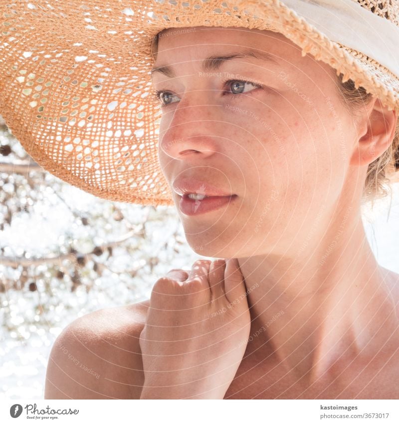 Nahaufnahme-Porträt einer ungeschminkten, natürlich schönen, sinnlichen Frau mit Stroh-Sonnenhut am Strand im Schatten einer Pinie. Sommer Person Dame jung MEER