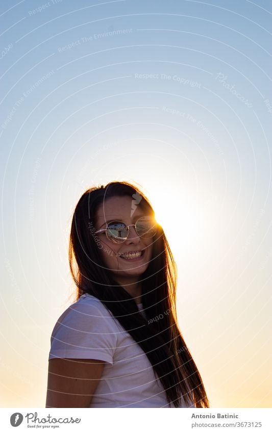 Attraktive Brünette mit Sonnenbrille lachend , Sonne direkt hinter dem Kopf spähend, goldene Sonnenuntergangsstunde. attraktiv Hintergrund schön Schönheit