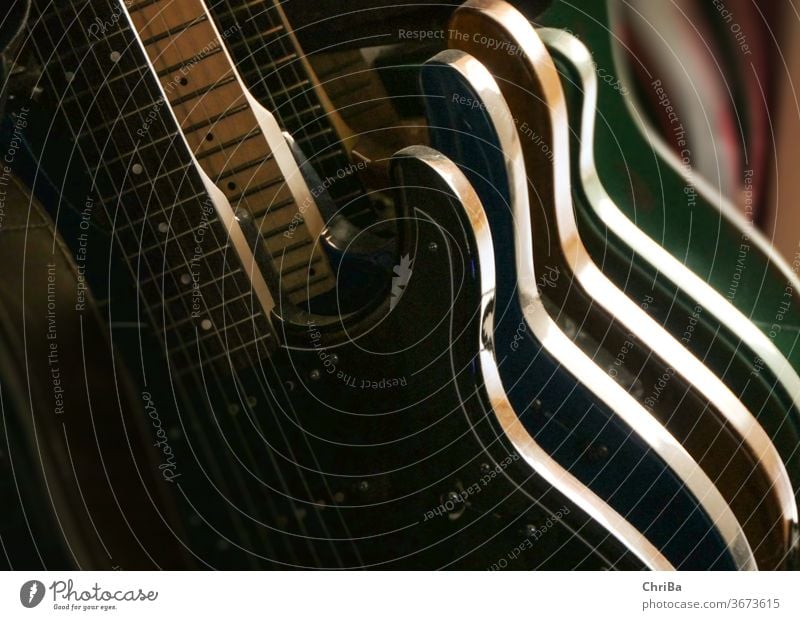 Gitarren im Ständer im Seitenlicht Gitarrenhals Gitarrenständer musik symbolisch gegenlicht streiflicht schatten gitarren Musikinstrument musizieren Klang Saite
