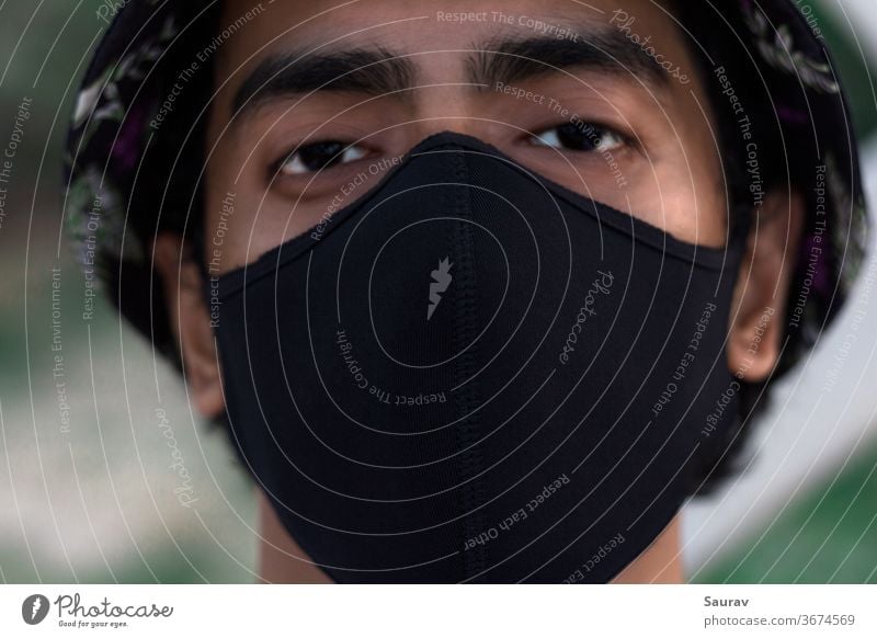 Nahaufnahme des Porträts eines jungen Jahrtausends, der eine schwarze Schutzmaske trägt, um eine Infektion mit dem Covid-19-Virus zu verhindern. Die neue Normalität während einer Weltpandemie.