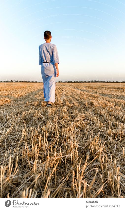 Eine Bäuerin geht durch ein gemähtes Weizenfeld in der Ukraine landwirtschaftlich Ackerbau authentisch Herbst Rücken blau Brot Bekleidung Land Landschaft Ernte