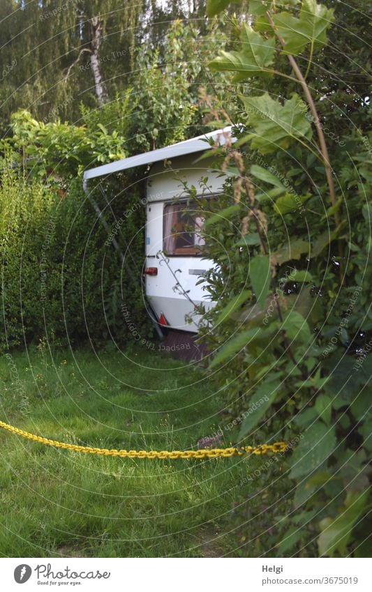 kein Zutritt - Wohnwagen steht zwischen Hecken , der Bereich ist mit einer gelben Kette abgesperrt Camping Campingplatz Pflanze Sträucher Wiese Gras