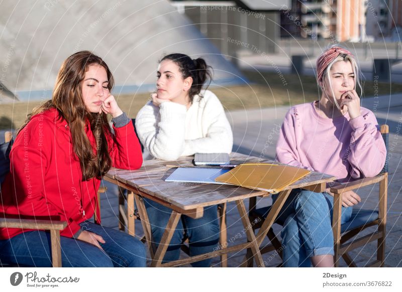 Verärgerte Freunde oder Mitbewohner, die in einem Café im Freien sitzen 3 wütend verärgert Freundschaft argumentierend Sitzen Frau Mädchen Zusammensein
