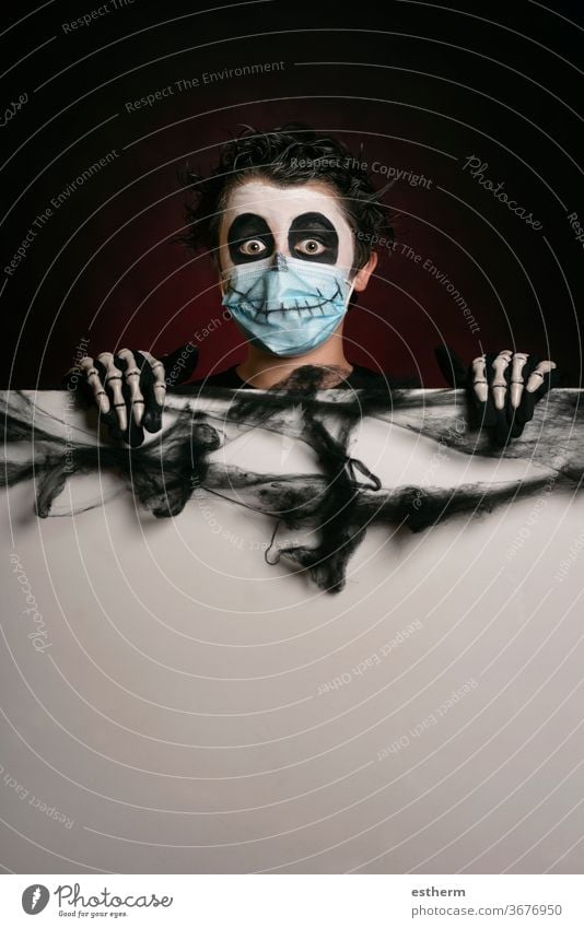 Happy Halloween. Kind mit medizinischer Maske in einem Skelettkostüm, das ein leeres Brett hält medizinische Maske Coronavirus covid-19 Party Spaß Schädel