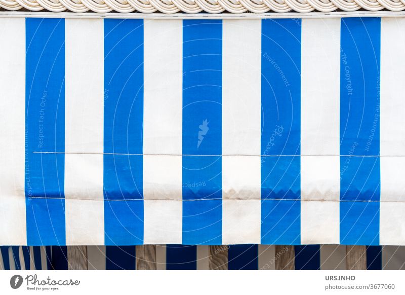 der blau weiß gestreifte Sonnenschutz am leeren Strandkorb verdeckt den Einblick Strandkorbvermietung sonnenschutz Dekor Sonnenblende Streifen