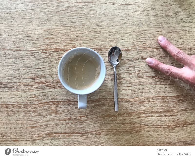 zwei Finger Kaffee mit Löffel Kaffeetrinken Kaffeetasse Tisch zwei finger Hand Tasse Getränk Heißgetränk Kaffeepause Espresso Café Kaffeetisch Frühstück