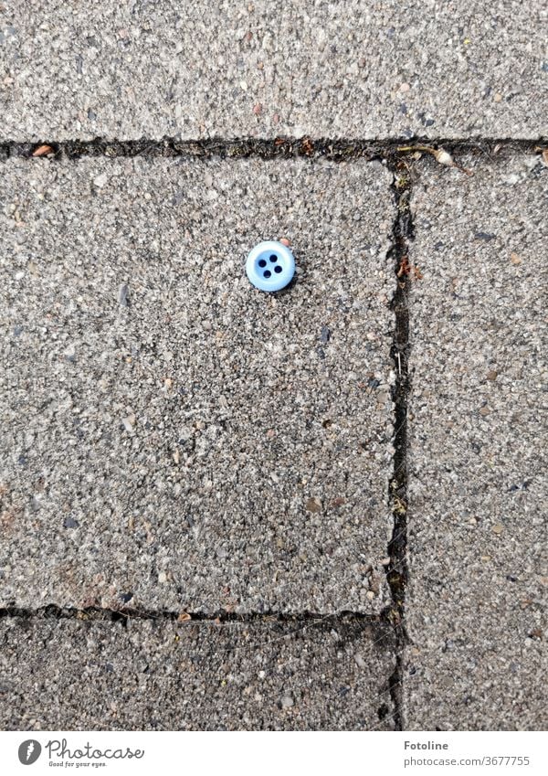 Jim Knopf - oder ein kleiner blauer Knopf liegt auf den Pflastersteinen eines Gehwegs Detailaufnahme Farbfoto Bekleidung Mode Menschenleer Nahaufnahme Tag
