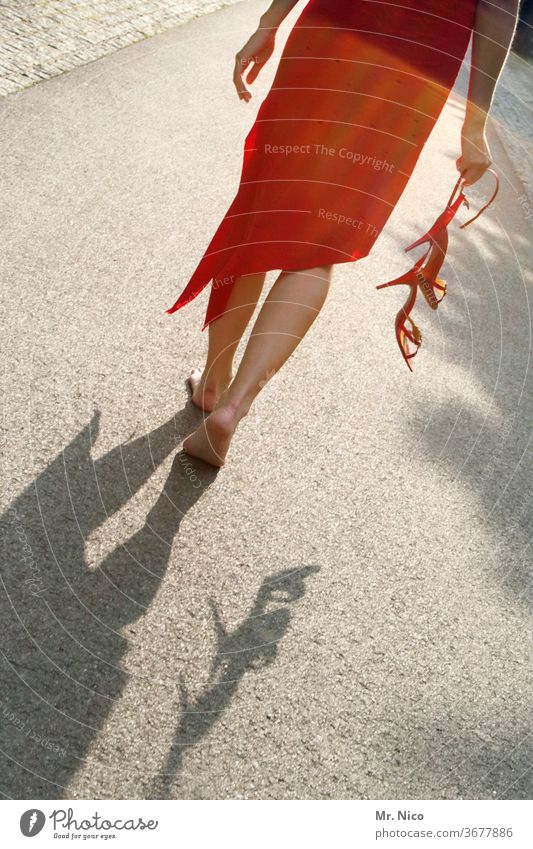Frau in einem roten Kleid geht barfuß über die Straße Schuhe ausziehen Sommerkleid Barfuß Beine Fuß Damenschuhe Haut Wade Asphalt Stöckelschuh festhalten