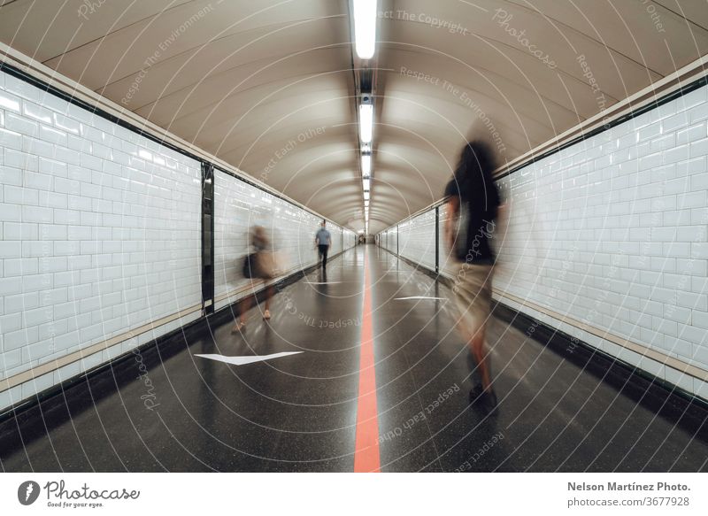 Verschwommene Personen, die in einem großen Tunnel eines Bahnhofs gehen. Die neue Normalität. Eine Gruppe von Menschen, die durch einen U-Bahn-Korridor eilt.