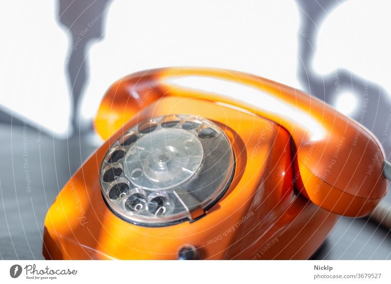 Telefonieren - orangenes Telefon "FeTAp 615" in orange mit Wählscheibe und Hörer (retro) im hellen Sonnenlicht Wählscheibentelefon Fetap Schnurtelefon