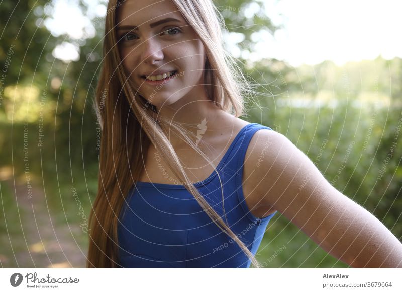 Seitliches Portrait einer jungen Frau in blauem Sommerkleid in der Natur Reinheit Glück Schönes Wetter Ausflug Erwartung Sonnenlicht Nahaufnahme Tag