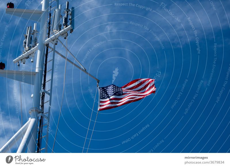 Die Flagge der Vereinigten Staaten von Amerika weht im Wind auf dem Deck eines großen Schiffes auf See mit Mobilfunkmasten amerika Amerikaner Transparente